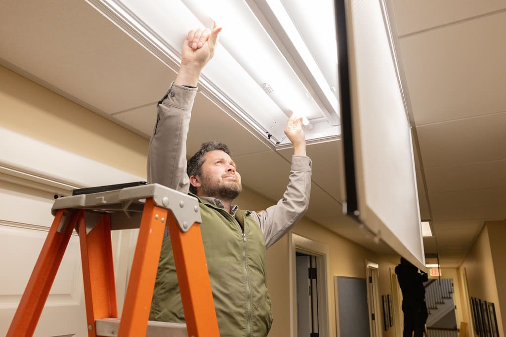 Electrician installing new LED lighting from a ladder